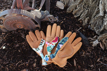 Load image into Gallery viewer, Pair of gardening gloves with floral patterns on a mulched surface