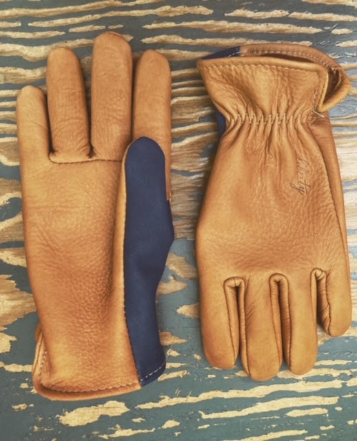 Top view of saddle tan gloves with two toned thumbs. Hot stamp branded Liberty