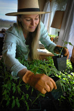 Load image into Gallery viewer, stylish woman wearing vintage stitched saddle tan deerskin gardening glove with reinforced palm while tending plants